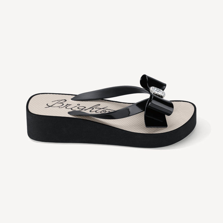 Side view of a black and white flip flop with a bow