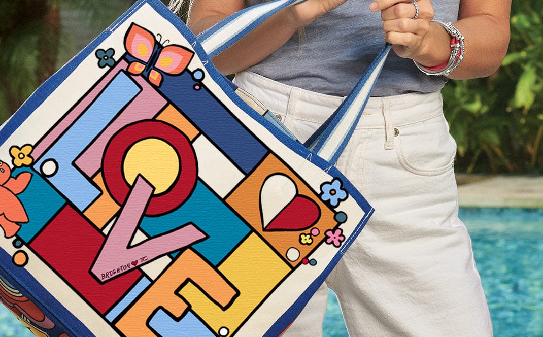 A picture of a model holding the Power Of Love Tote bag in front of a pool