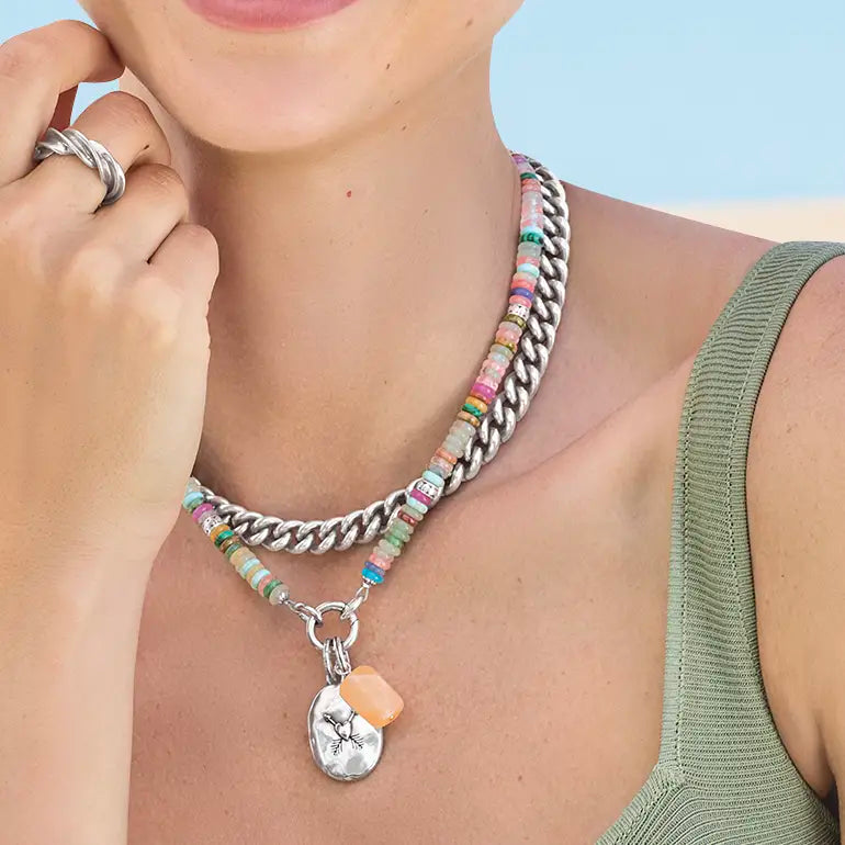 Close-up of a person wearing a Brighton colorful beaded necklace with a silver chain and pendant.