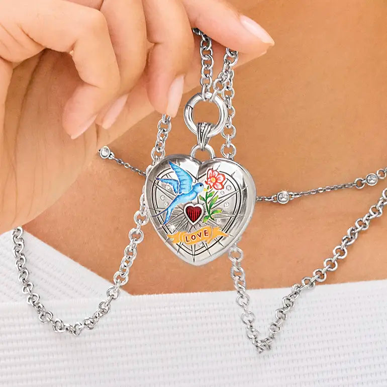 Brighton Silver locket with heart design and 'LOVE' engraving held by a hand