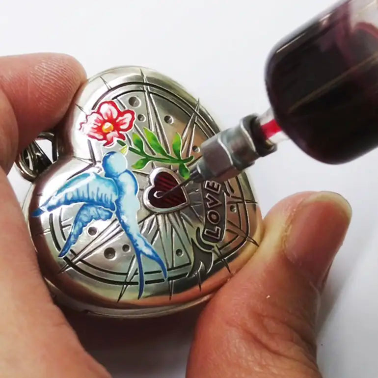 Person pouring liquid into a decorative Brighton locket with artistic designs.
