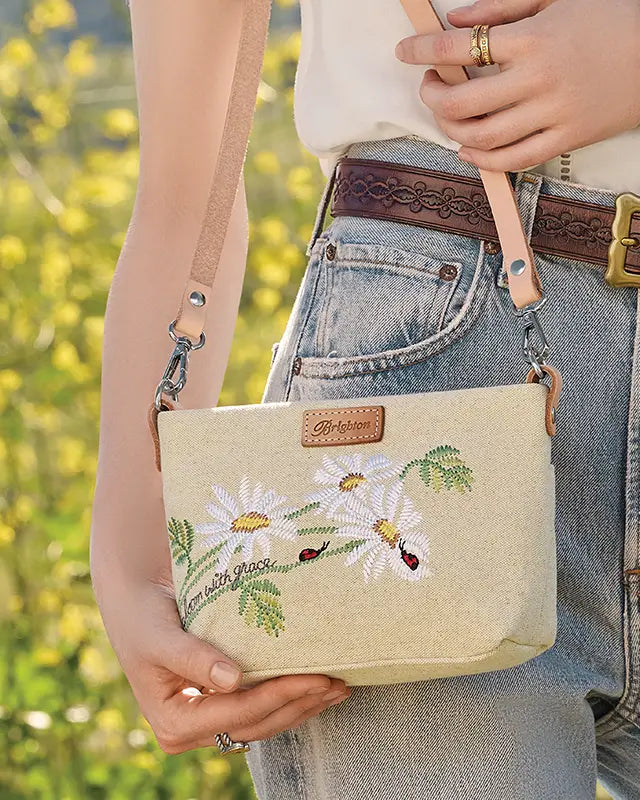 Brighton Beige handbag with floral embroidery held by a person outdoors