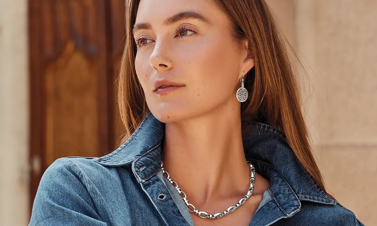 Woman wearing a denim jacket and Brighton silver necklace with a blurred background