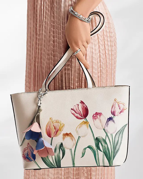 Brighton Handbag with floral design held by a person wearing a pink dress.