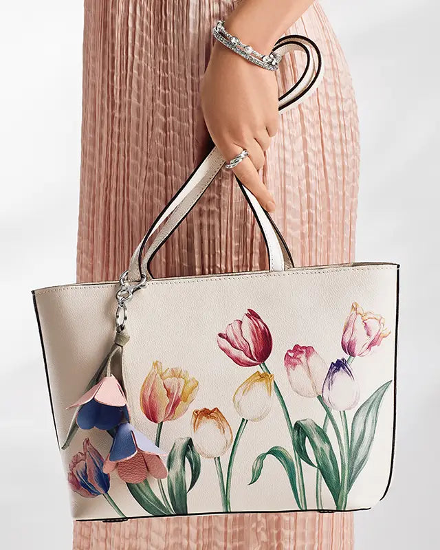 Brighton Handbag with floral design held by a person wearing a pink dress.