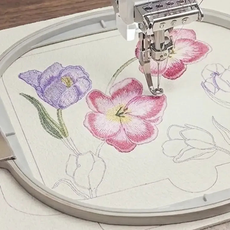 Embroidery hoop with floral design being embroidered on a white fabric.