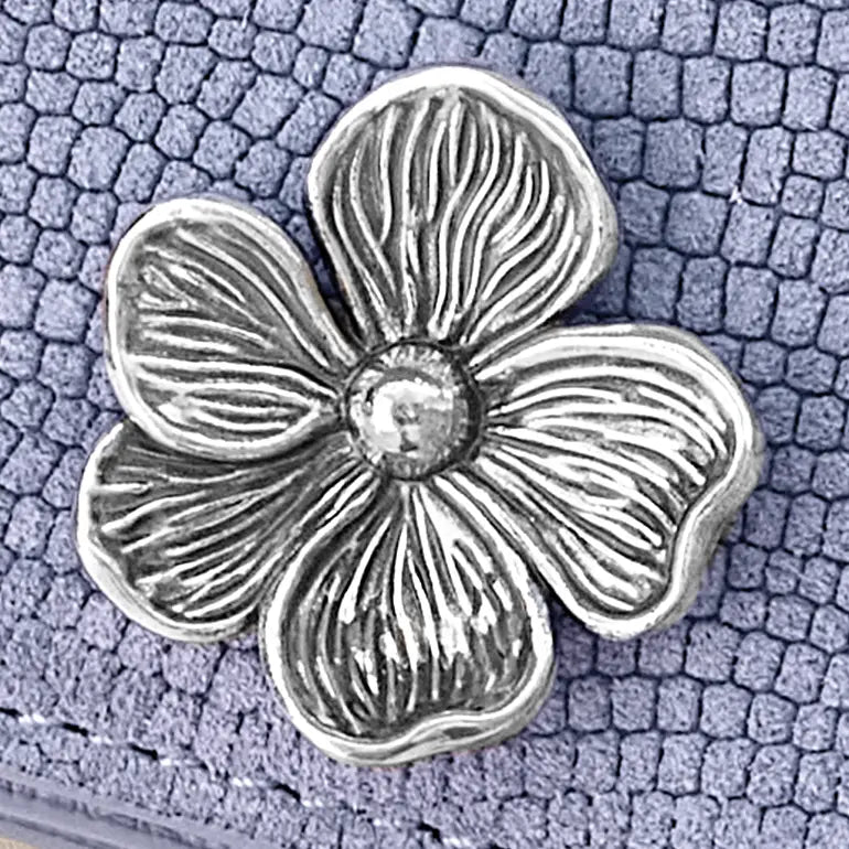 Silver flower-shaped object on a textured purple surface