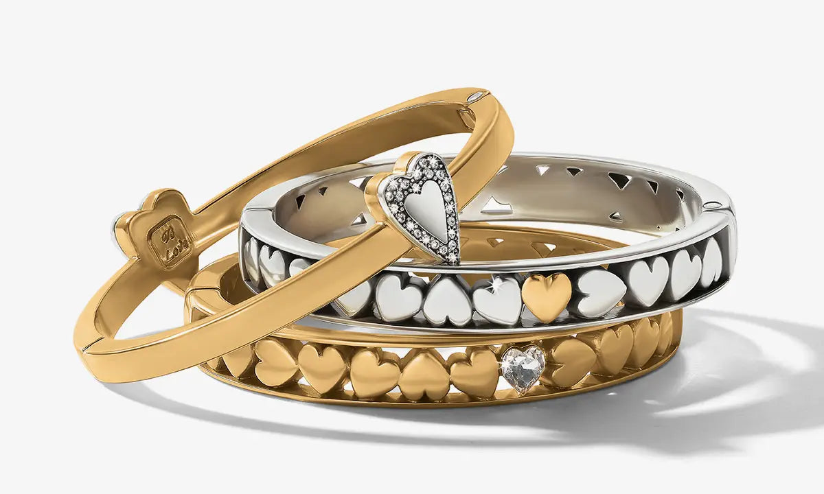 Three gold and silver bracelets with heart designs on a white background