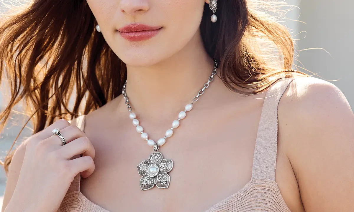Woman wearing a pearl necklace and earrings with a neutral background