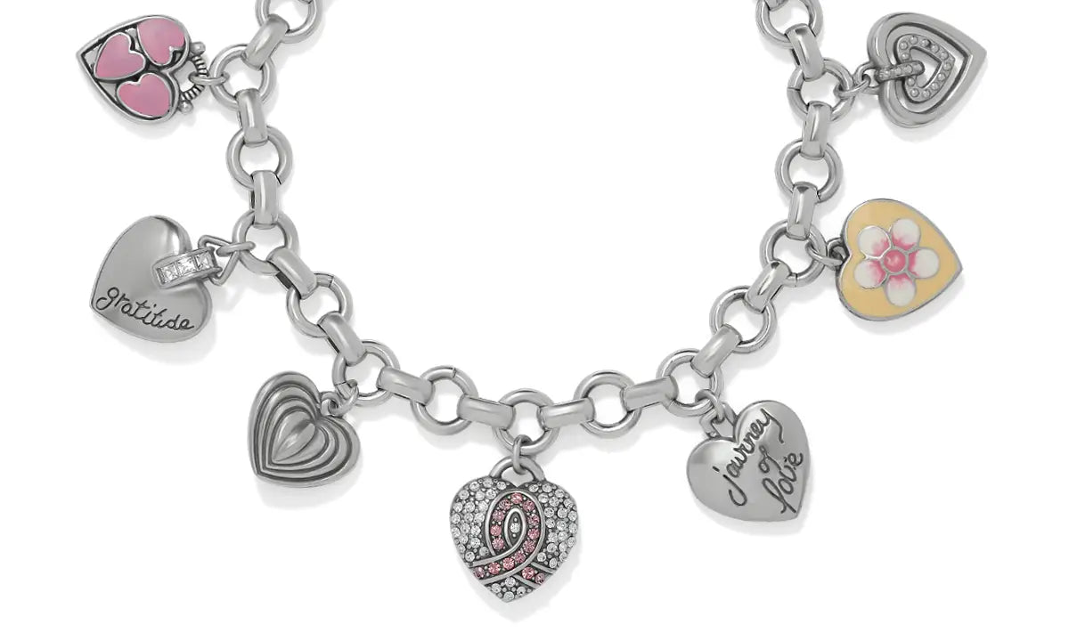 A silver-tone charm bracelet featuring multiple heart-shaped charms, including engraved names, a pink-and-white floral charm, and a heart with a pink ribbon design, shown on a white background.