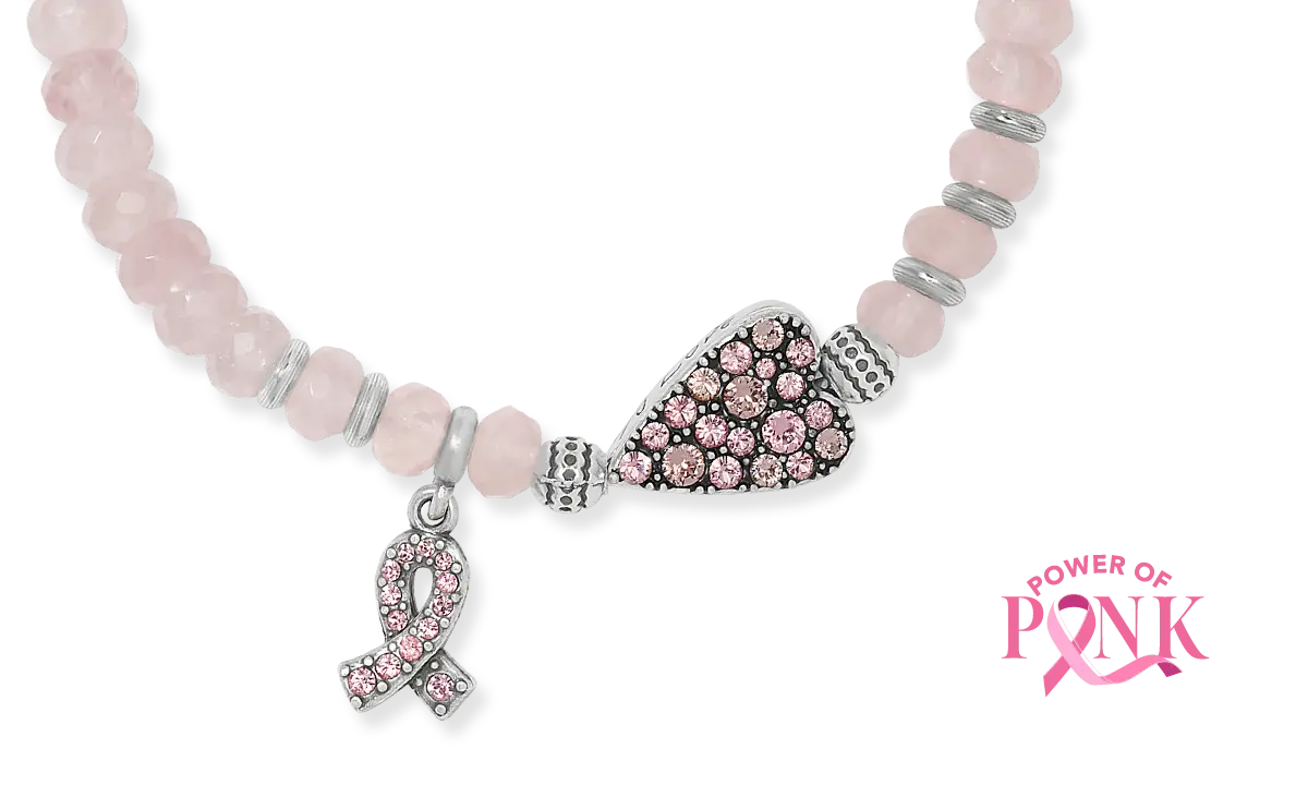 A pink beaded bracelet with a silver-toned heart-shaped charm paved with pink stones and a matching pink ribbon charm, shown on a white background with a 'Power of Pink' logo in the bottom right corner.