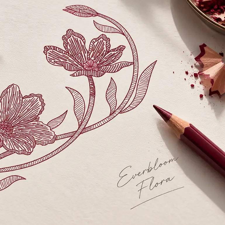 A close-up of a colored pencil sketch of floral vines on textured paper, with the words 'Everbloom Flora' written nearby and a pencil shavings prop in the corner.