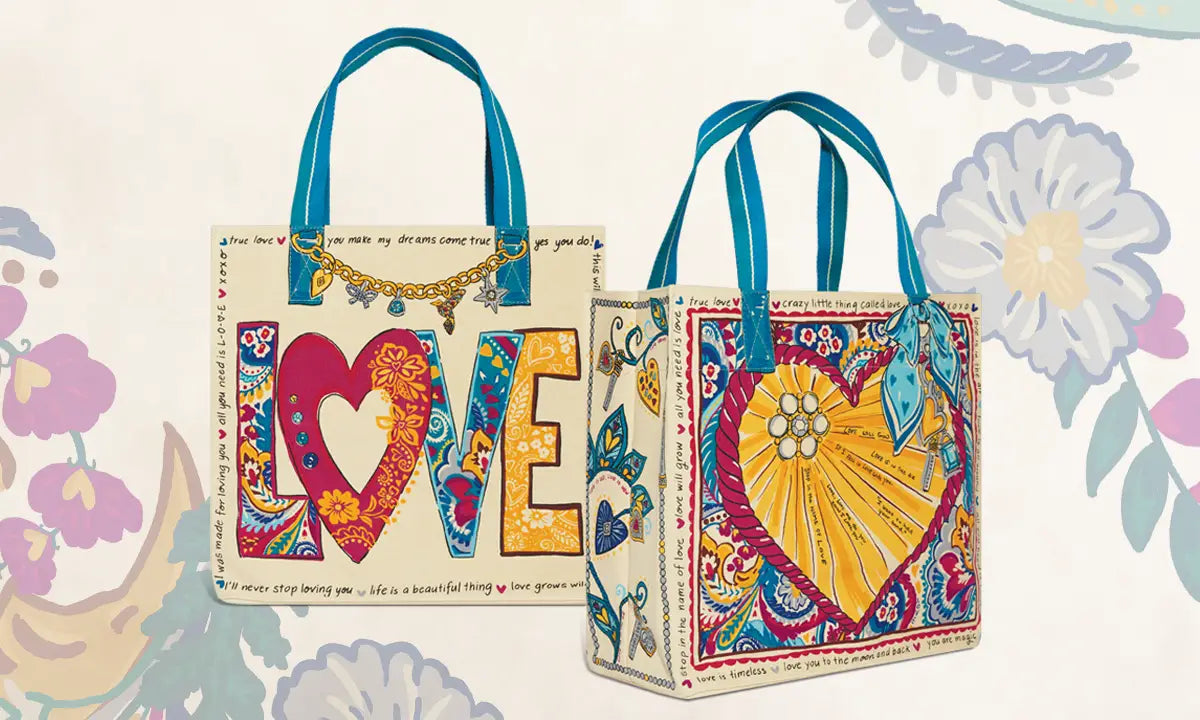 Two decorative tote bags with blue handles, shown against a light floral background. The left bag features the word LOVE in large colorful letters with a heart-shaped O.