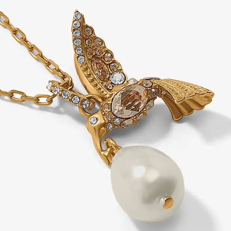 Gold-tone bird pendant necklace with clear rhinestones, a faceted amber-brown center stone, and a large white pearl drop, shown on a clean white background.