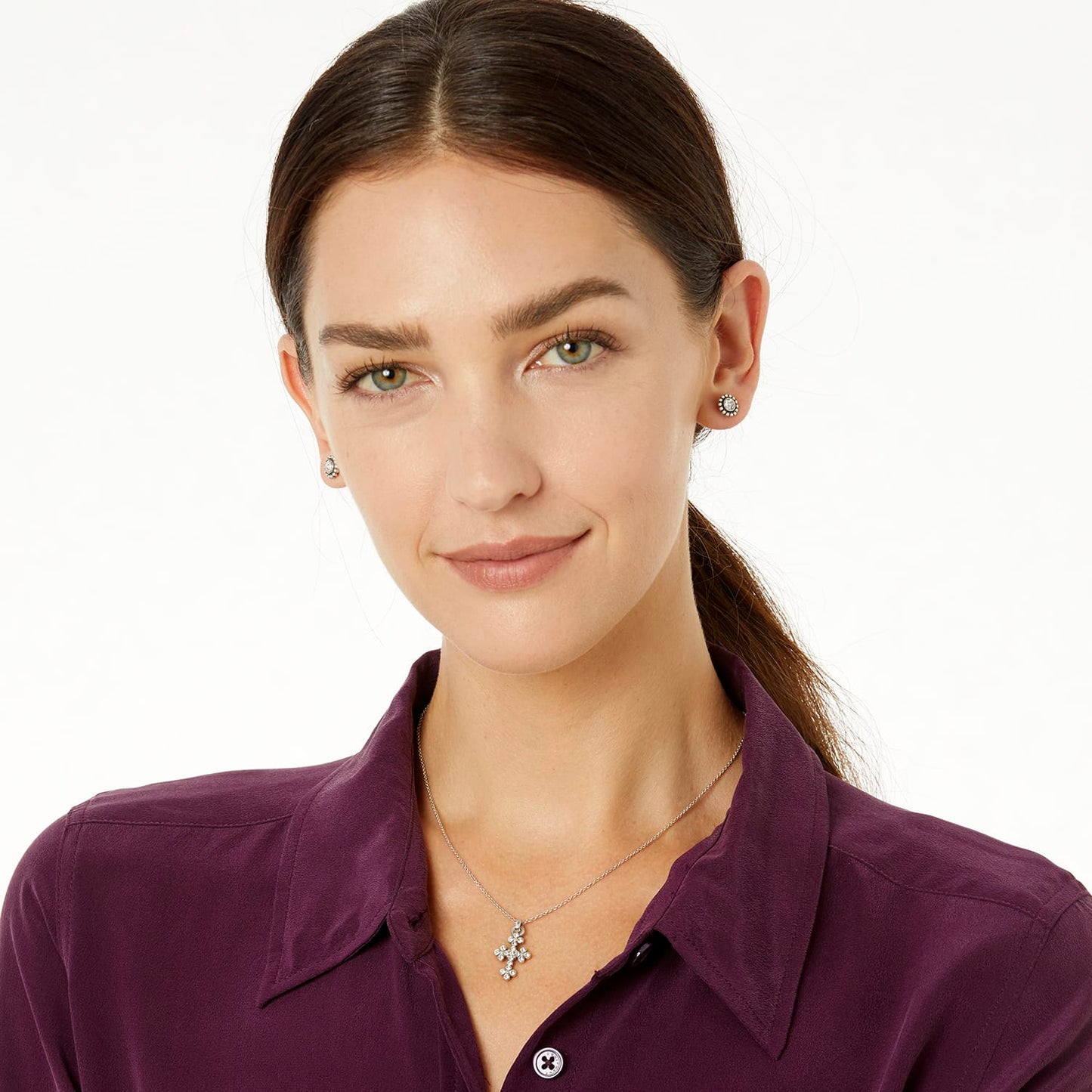 Model wearing a Brighton silver cross pendant necklace with crystal accents paired with matching crystal stud earrings