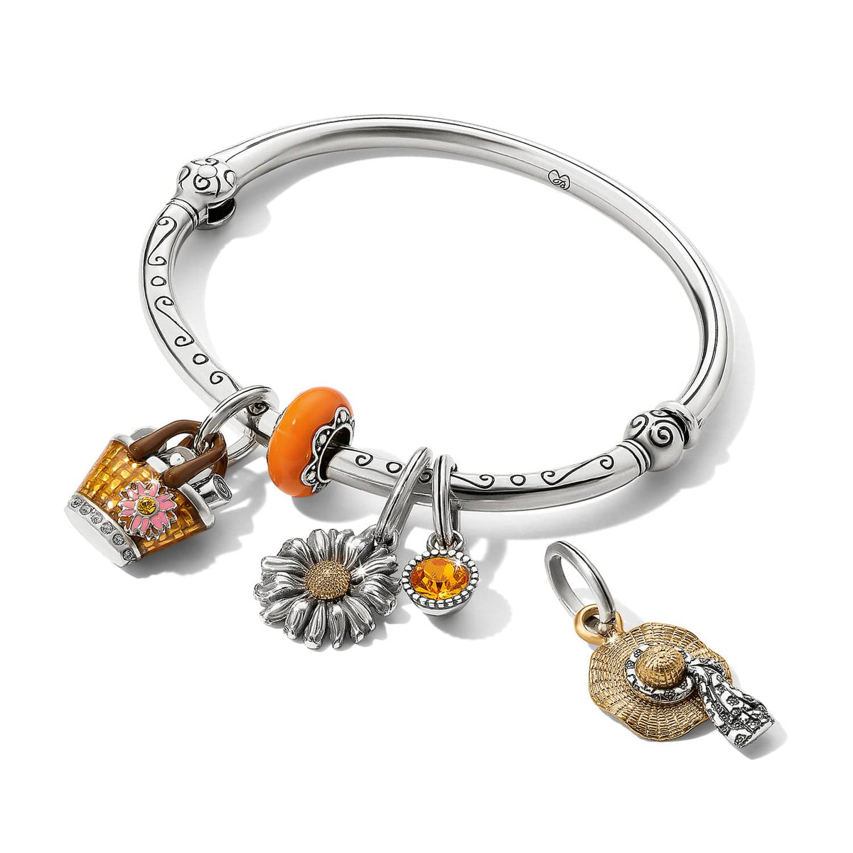 Brighton silver-tone bangle bracelet with floral, daisy, orange bead, crystal, and two-tone straw hat charms on a white background