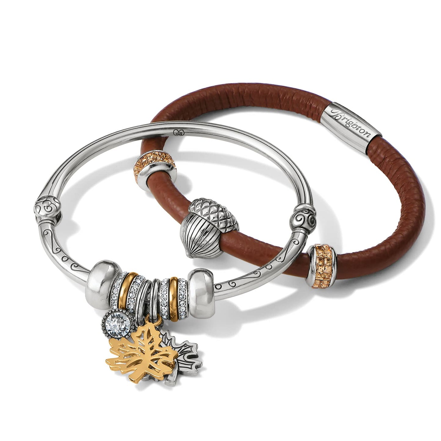 Brighton bangle and brown leather bracelet set with silver-plated charms, crystal accents, and gold leaf pendants on a white background