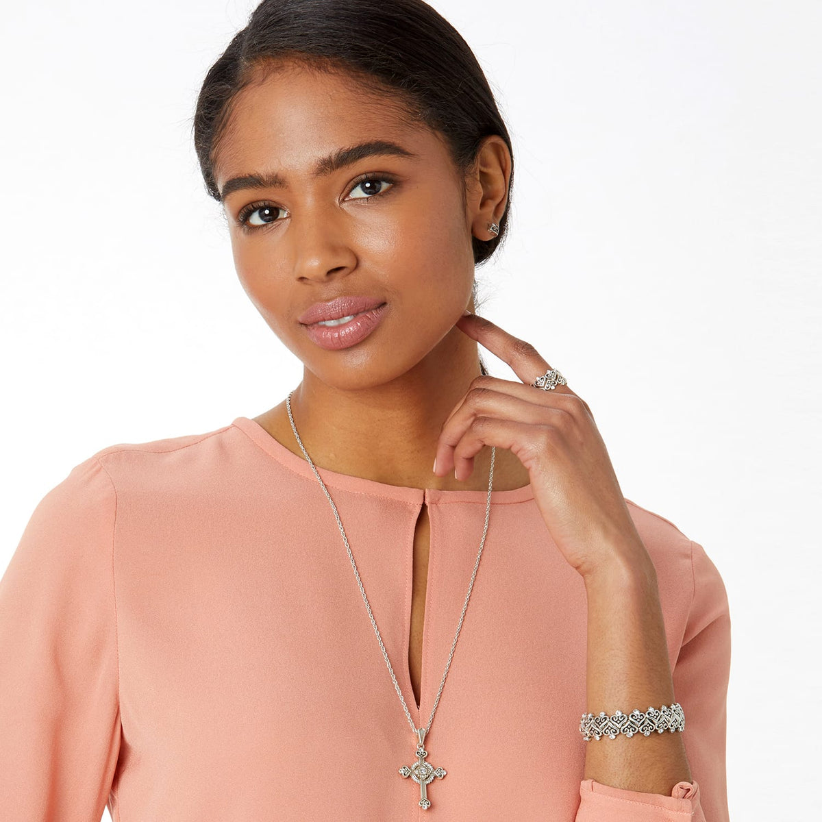 Model wearing a Brighton silver-plated cross pendant necklace with crystals and coordinating Brighton accessories