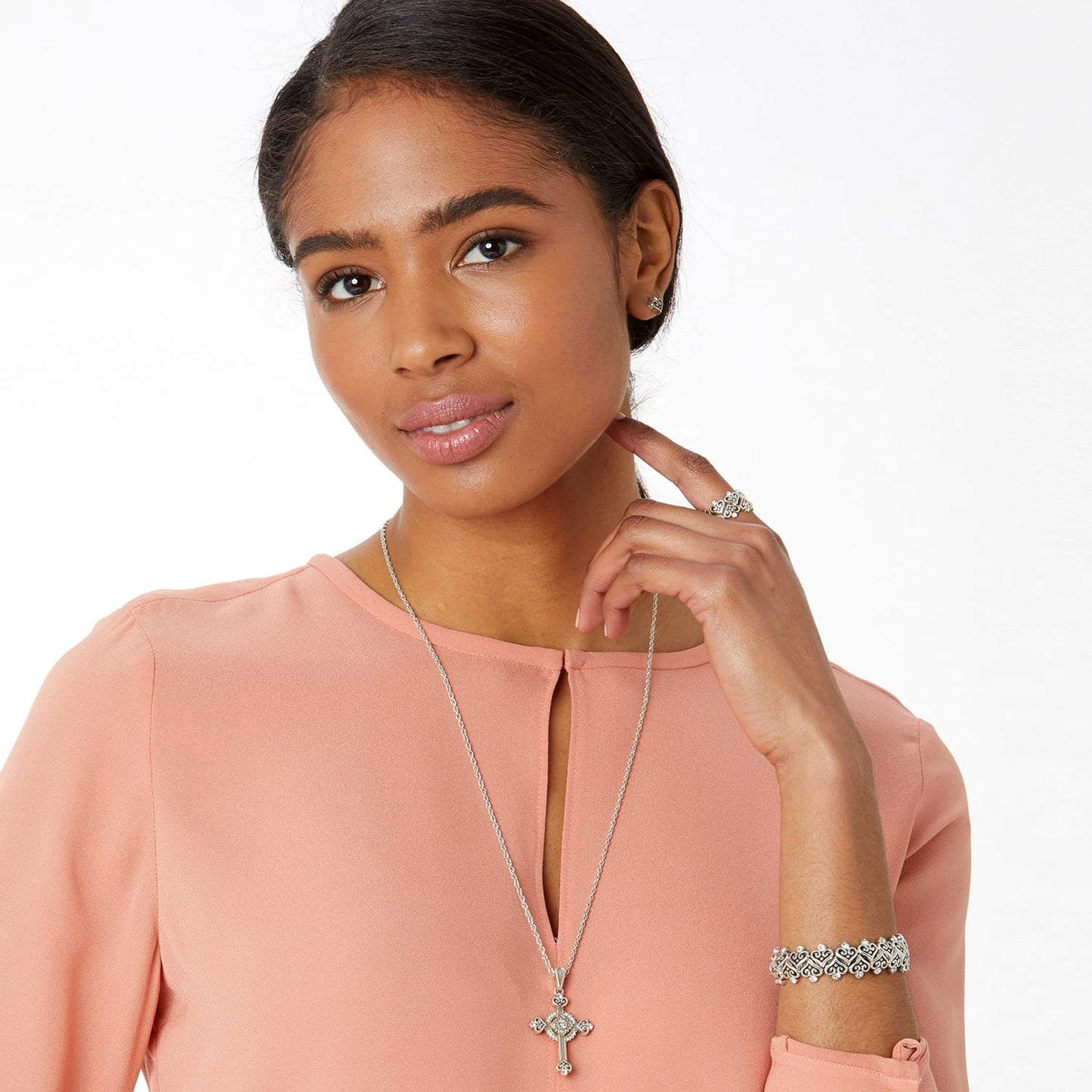 Model wearing a Brighton silver-plated cross pendant necklace with crystals and coordinating Brighton accessories