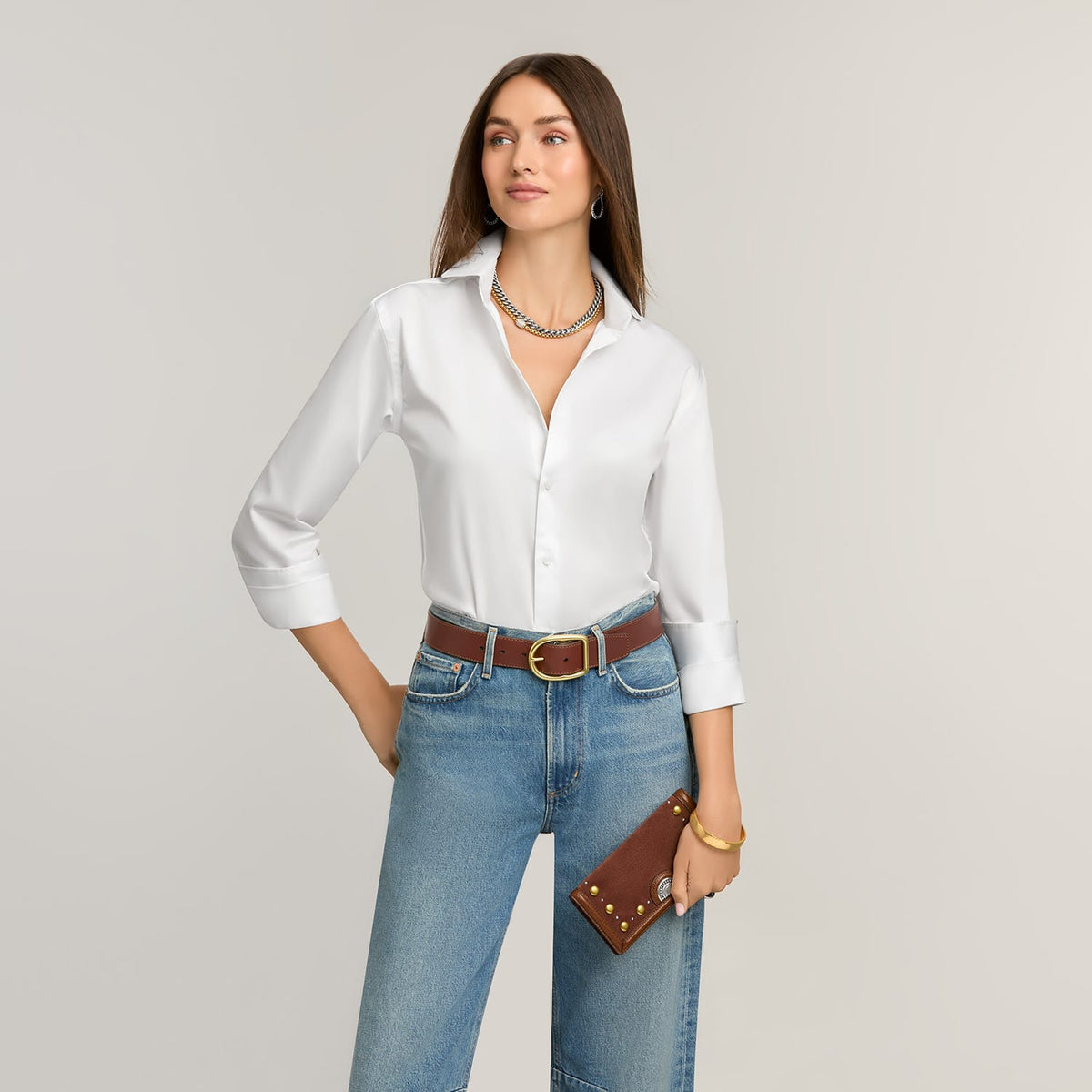 Model wearing a Brighton brown leather belt with gold-tone buckle, styled with a Brighton studded leather wallet