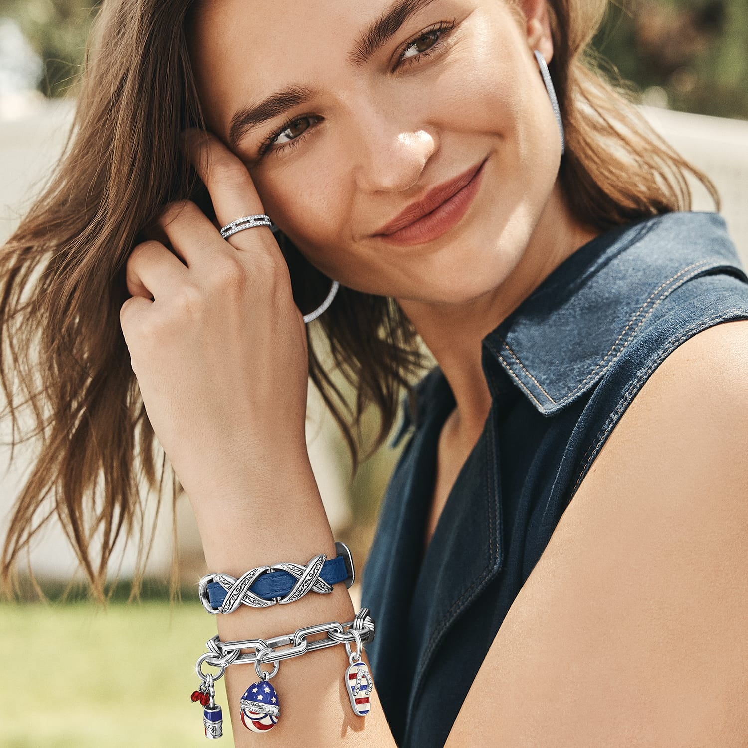 Model wearing a Brighton silver-plated charm bracelet with patriotic enamel charms and coordinating Brighton accessories