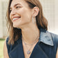 Model wearing a Brighton silver-plated hoop earring with layered necklaces and a crystal heart pendant in red, white, and blue