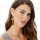 Model wearing a Brighton drop earring with gold-tone charm, crystal accent, and golden tassel fringe