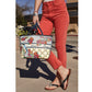 Brighton tote handbag with floral print, blue bird illustration, and Love script, styled with black thong sandals