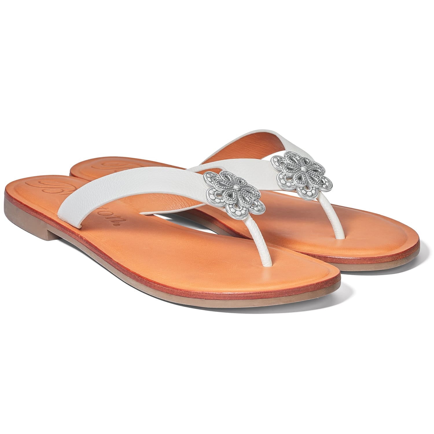 Brighton white leather thong sandals with silver-tone floral medallion accents and tan footbeds on a white background