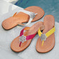 Brighton thong sandals in white, pink, and yellow with silver-tone floral medallions, styled poolside on stone tile