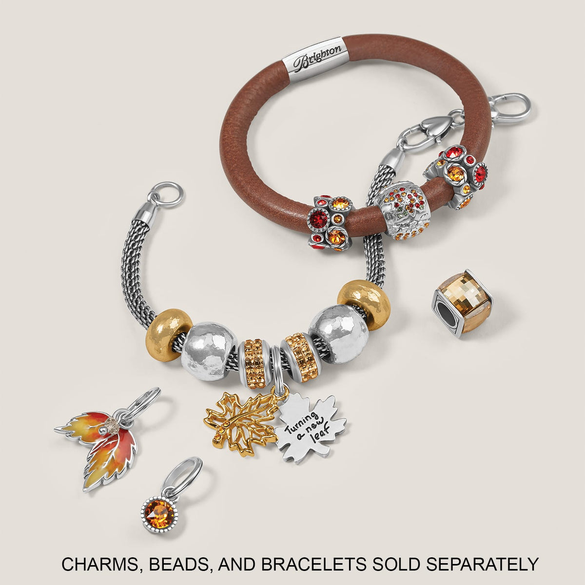 Brighton bracelets styled with silver-plated leaf charms and crystal beads in amber and red tones on neutral background