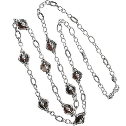 Brighton long chain necklace with wire-wrapped deep red faceted stones and sterling silver links on a white background