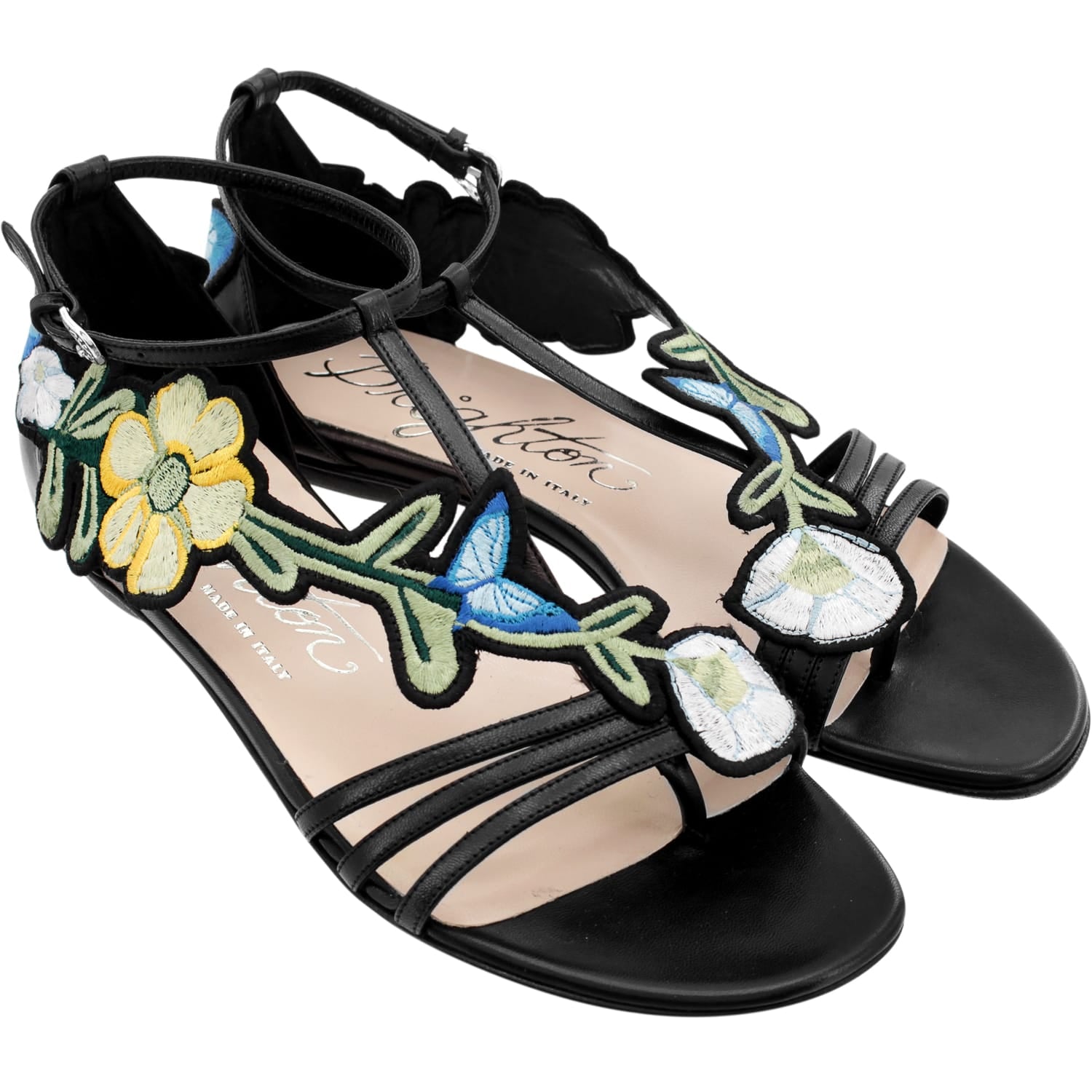 Brighton black leather ankle-strap sandals with embroidered floral appliqués in yellow, blue, and green on a white background
