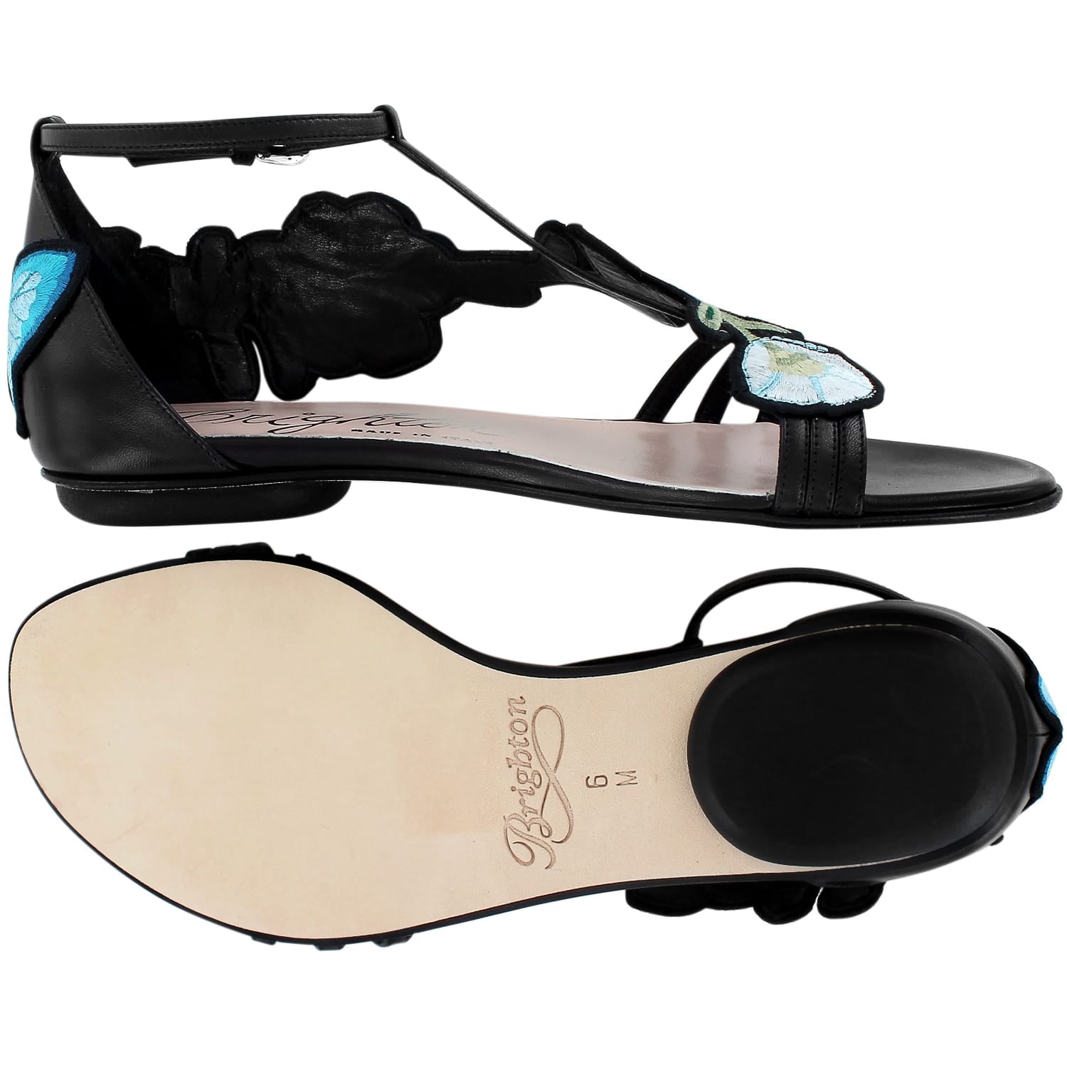 Brighton flat sandals in black leather with blue floral embroidery and T-strap design, sole view shown, on a white background
