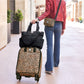 Model with a Brighton leopard print rolling suitcase, black quilted tote, and coordinating leopard crossbody bag