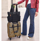 Model with a Brighton leopard print rolling suitcase styled with a black quilted tote bag on top