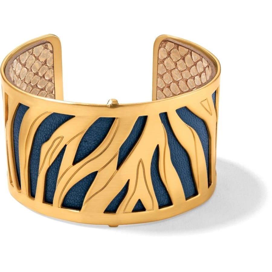 Brighton gold-plated cuff bracelet with cutout tiger stripe design over blue and snake-print leather on a white background