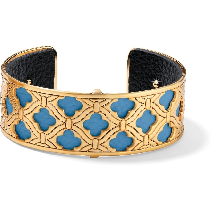 Brighton cuff bracelet with gold-plated quatrefoil lattice design, blue stone inlays, and black leather interior on a white background