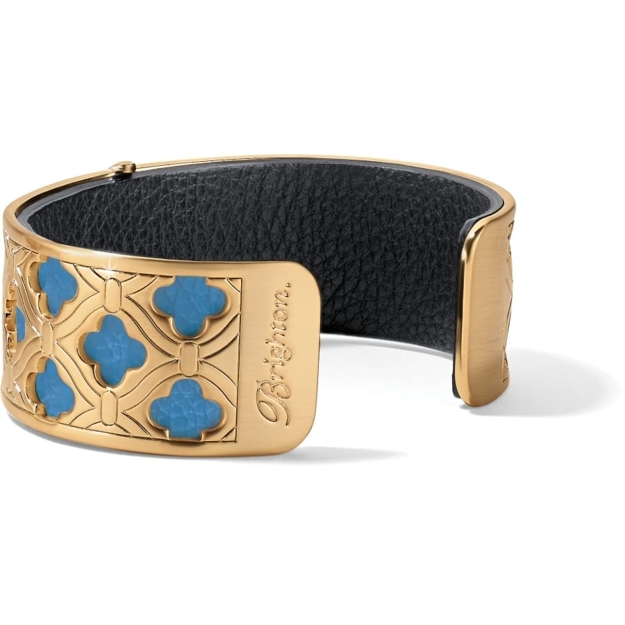 Brighton cuff bracelet with gold-plated quatrefoil openwork design, turquoise accents, and black leather interior on a white background