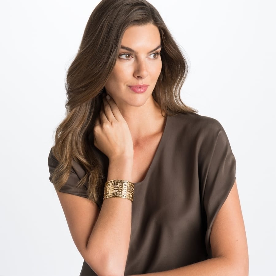 Model wearing a Brighton gold-plated wide cuff bracelet with textured openwork design and crystal accents
