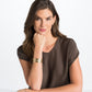 Model wearing a Brighton gold-plated cuff bracelet with openwork scroll design paired with gold-plated stud earrings