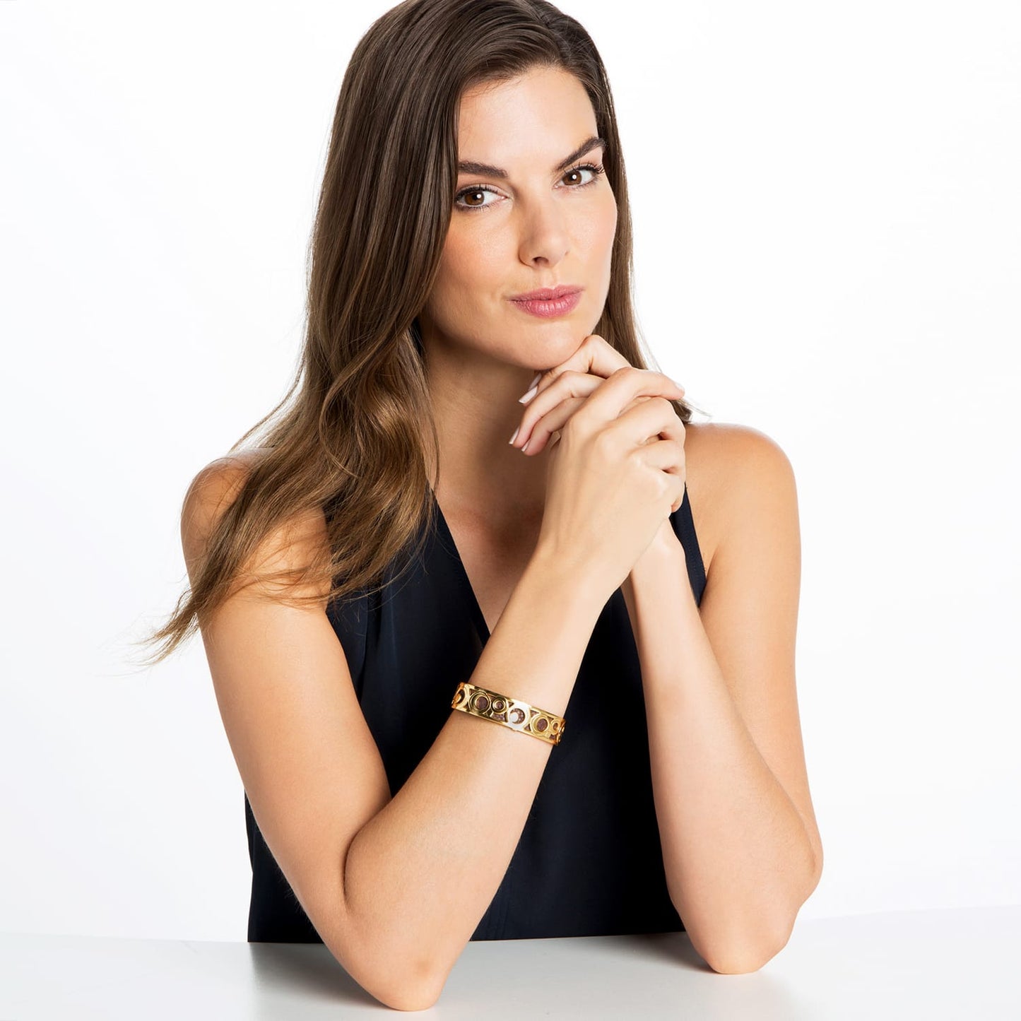 Model wearing a Brighton gold-plated bangle bracelet with circular openwork design and inset stone accents