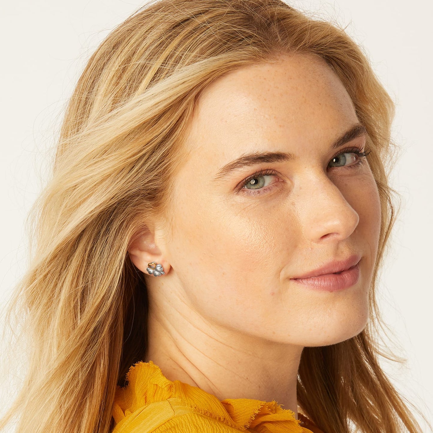 Model wearing Brighton stud earrings with two-tone floral design featuring silver petals and a gold heart accent