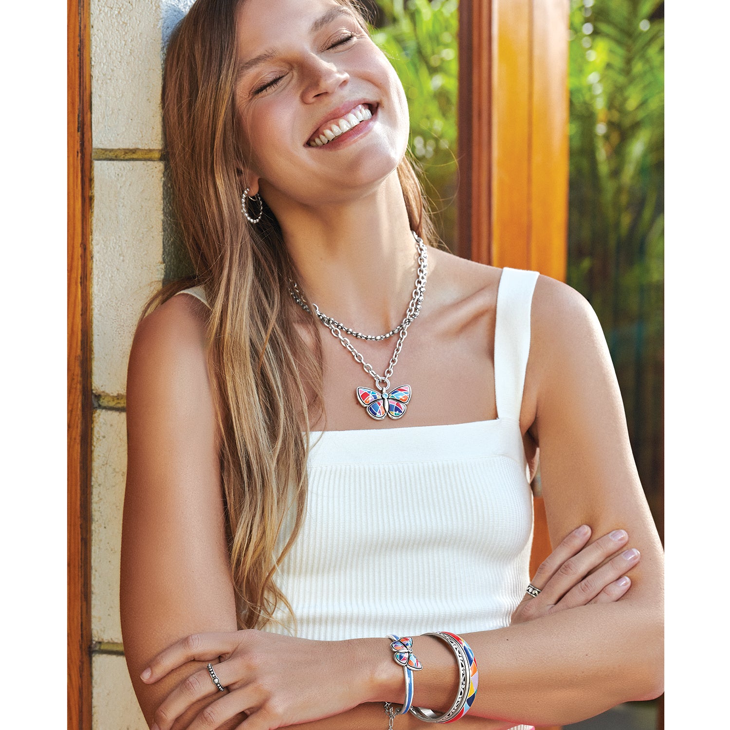Model wearing a Brighton silver-plated butterfly pendant necklace with colorful enamel wings and coordinating Brighton accessories