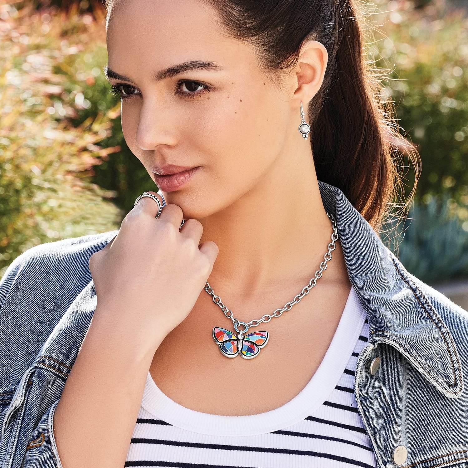 Model wearing a Brighton silver-plated butterfly pendant necklace with colorful enamel wings and coordinating Brighton accessories