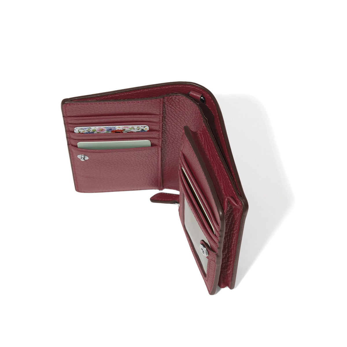 Brighton burgundy leather wallet shown open with interior card slots and floral-printed card on a white background