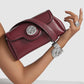 Brighton burgundy leather handbag with silver medallion accent and braided detail, styled with a silver cuff bracelet