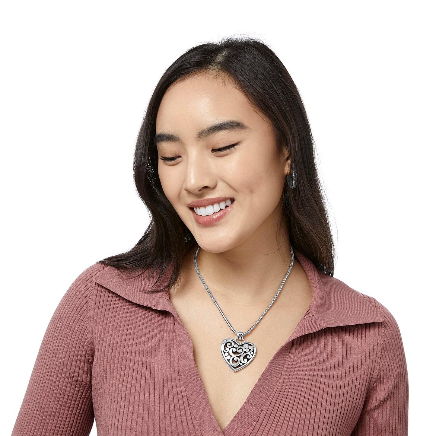 Model wearing a Brighton silver-plated heart pendant necklace with openwork scroll design on a snake chain