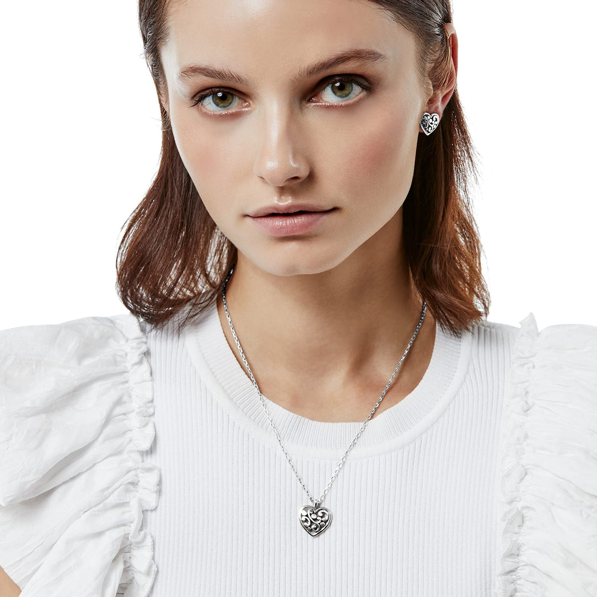Model wearing a Brighton silver-plated heart pendant necklace paired with matching filigree heart stud earrings