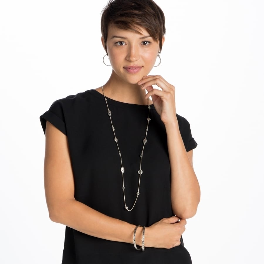 Model wearing a Brighton long silver-plated station necklace with crystal accents and coordinating hoop earrings and bracelet